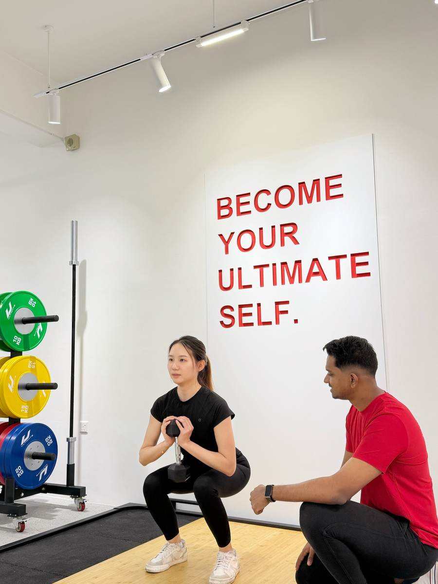 UFL coach guiding client through squat form in private studio
